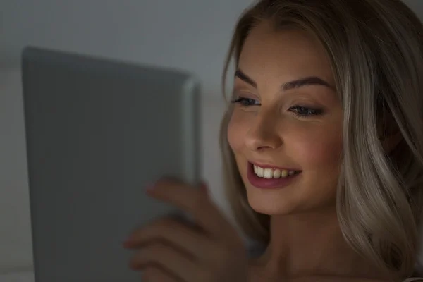 Mujer joven con tableta pc en la cama por la noche —  Fotos de Stock