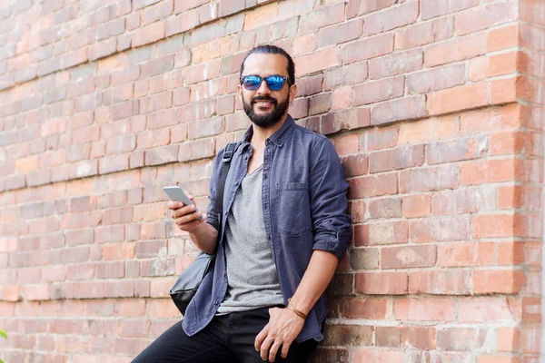 Man with backpack texting on smartphone in city — Stock Photo, Image