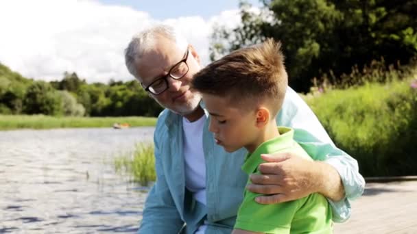 Grandfather and grandson sitting on river berth 24 — Stock Video