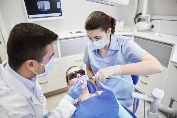 Dentistas que tratan dientes masculinos de pacientes en la clínica —  Fotos de Stock