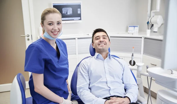 Ευτυχισμένη γυναίκα οδοντίατρος με άνδρα ασθενή στην κλινική — Φωτογραφία Αρχείου