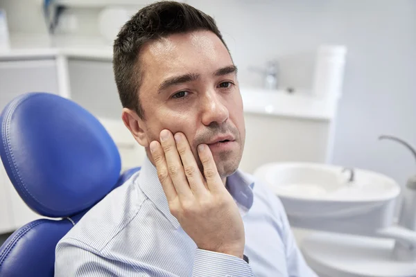 Чоловік має зубний біль і сидить на стоматологічному стільці — стокове фото