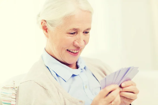 Glückliche Seniorin spielt zu Hause Karten — Stockfoto