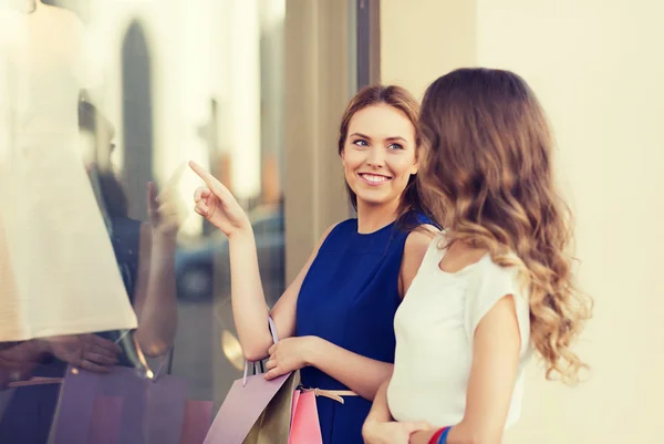 Mujeres felices con bolsas de compras en el escaparate —  Fotos de Stock