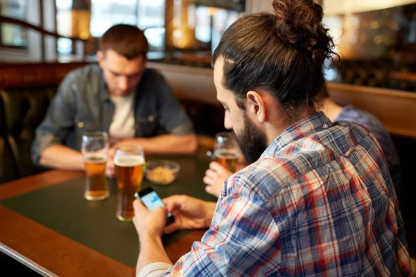 Close up de homens com smartphones e cerveja no bar — Fotografia de Stock