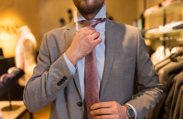 Close up of man tying tie at clothing store mirror — Stock Photo, Image