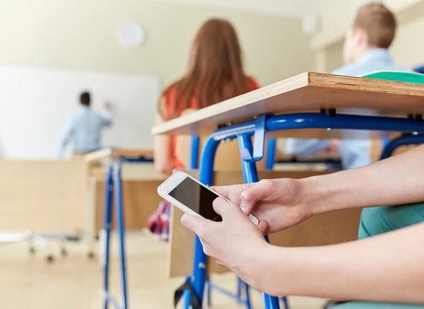 Estudiante chico con teléfono inteligente mensajes de texto en la escuela —  Fotos de Stock