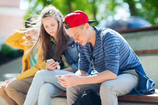Amigos adolescentes felizes com smartphones ao ar livre — Fotografia de Stock