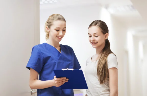 Doctor or nurse with clipboard and girl patient — Stock Photo, Image