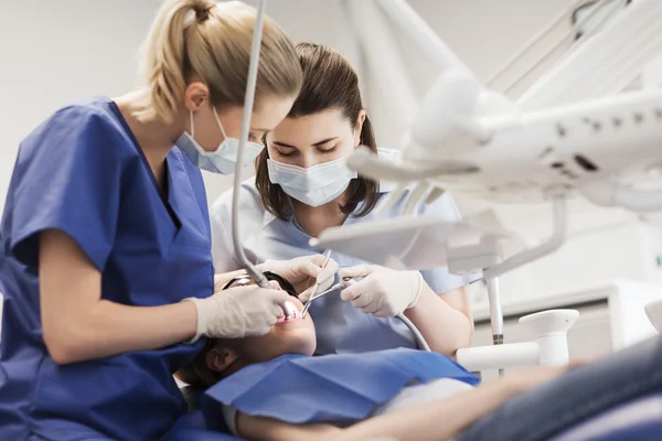 Dentistas mulheres que tratam os dentes da menina paciente — Fotografia de Stock