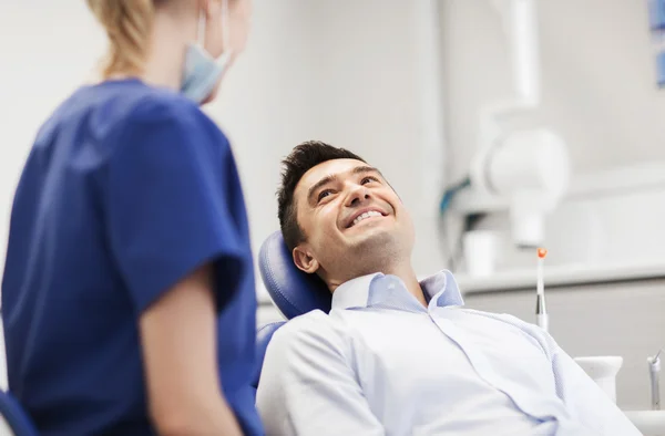 Γυναίκα οδοντίατρος με ευτυχισμένο αρσενικό ασθενή στην κλινική — Φωτογραφία Αρχείου