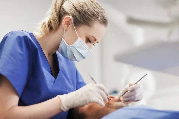 Dentista feminino verificando dentes de paciente do sexo masculino — Fotografia de Stock