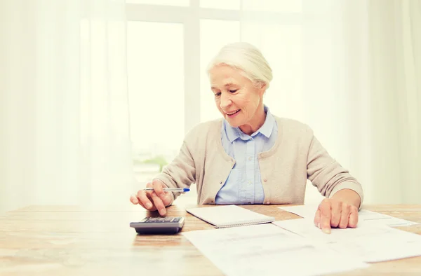 Senior woman with papers and calculator at home — Stock Photo, Image