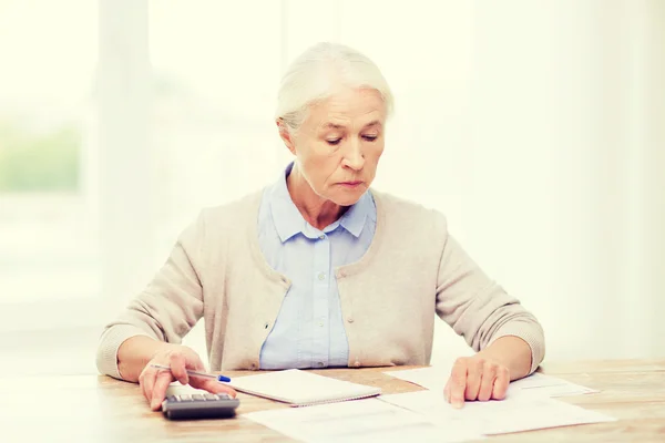 Donna anziana con carte e calcolatrice a casa — Foto Stock