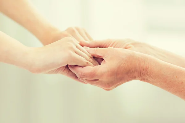 Primer plano de la mujer mayor y joven tomados de la mano — Foto de Stock