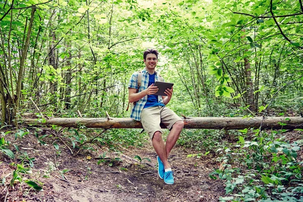 Glücklicher Mann mit Rucksack und Tablet-PC im Wald — Stockfoto