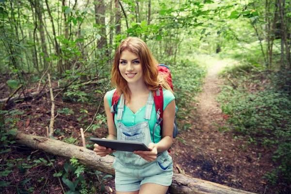 Gelukkige vrouw met rugzak en tablet pc in bos — Stockfoto
