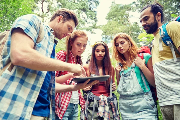 Gelukkige vrienden met rugzakken en tablet pc wandelen — Stockfoto