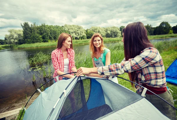 Amici sorridenti che installano tenda all'aperto — Foto Stock