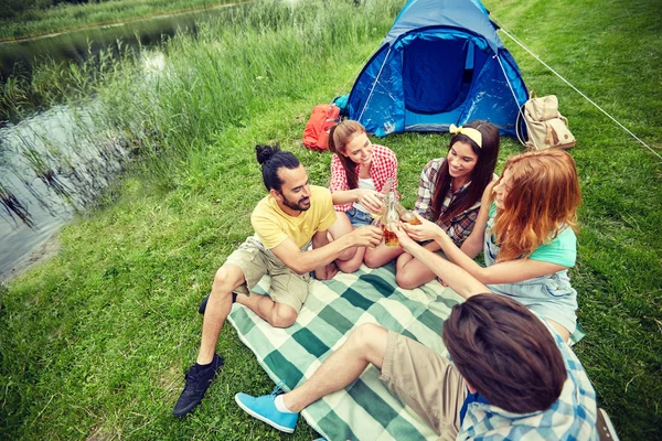 Amigos felizes com tenda e bebidas no parque de campismo — Fotografia de Stock