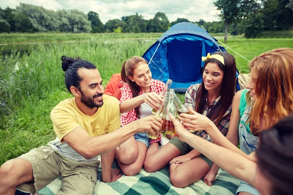 Happy friends with tent and drinks at campsite — Stock Photo, Image