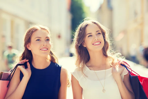 Gelukkig vrouwen met boodschappentassen wandelen in de stad — Stockfoto