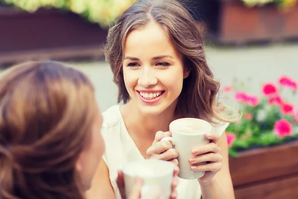 Smiling young women with coffee cups at cafe — Stock Photo, Image