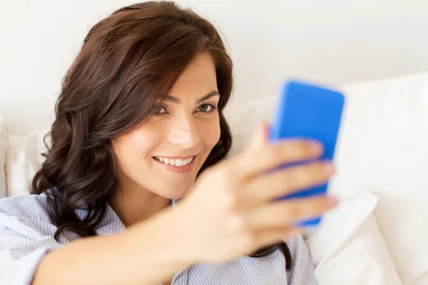 幸福的女人在家里考虑与智能手机的拍照 — 图库照片