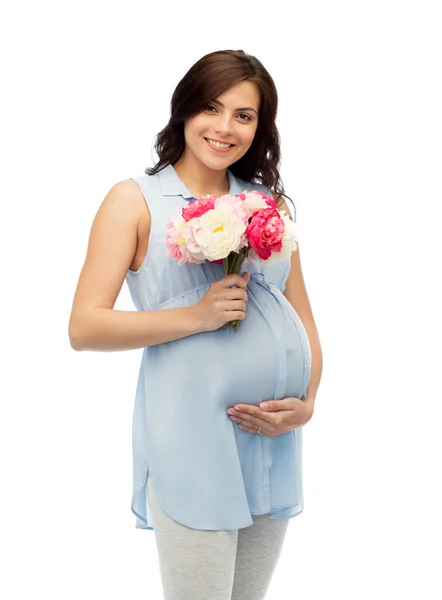 Щаслива вагітна жінка з квітами, що торкаються живота — стокове фото
