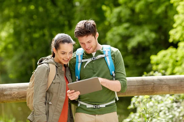 Gelukkige paar met rugzakken en tablet pc buitenshuis — Stockfoto