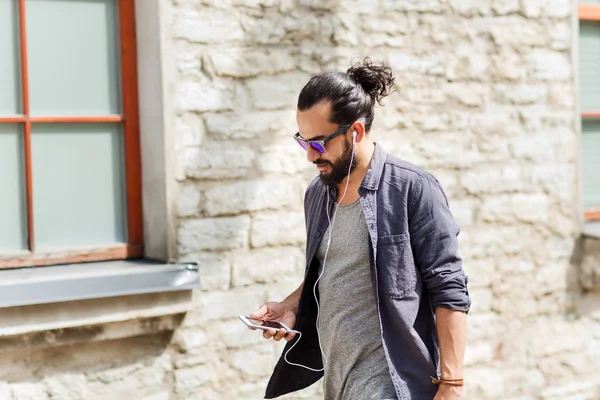 Man with earphones and smartphone walking in city — Stock Photo, Image