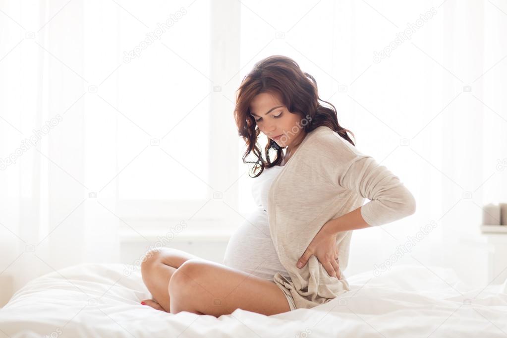 Pregnant woman with backache in bed at home — Stock Photo © Syda_Productions 119191402
