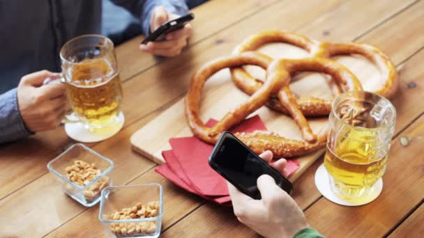 Amigos varones con smartphones bebiendo cerveza en el bar — Vídeo de stock