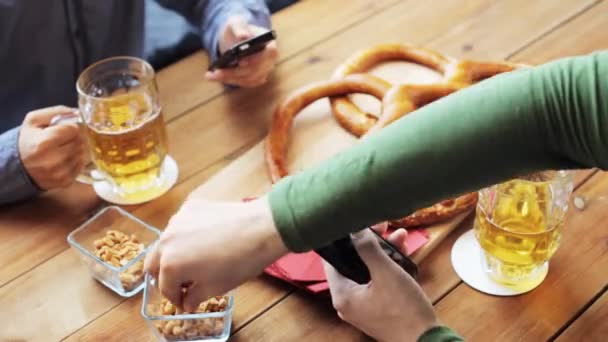 Друзья со смартфонами пьют пиво в баре — стоковое видео