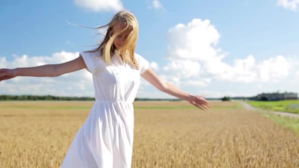Glimlachende jonge vrouw in witte jurk op graanveld — Stockvideo