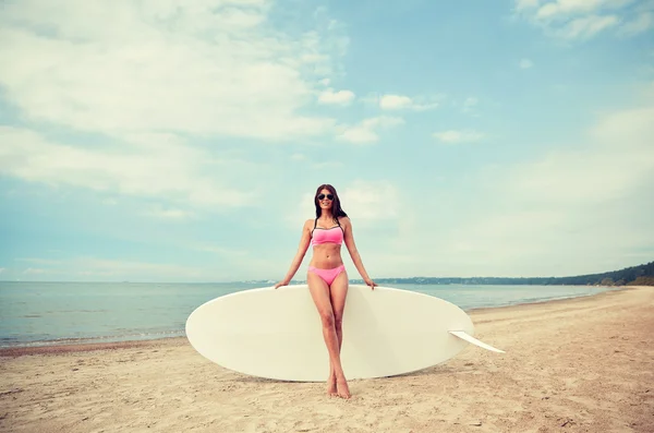 Sonriente joven con tabla de surf en la playa — Foto de Stock