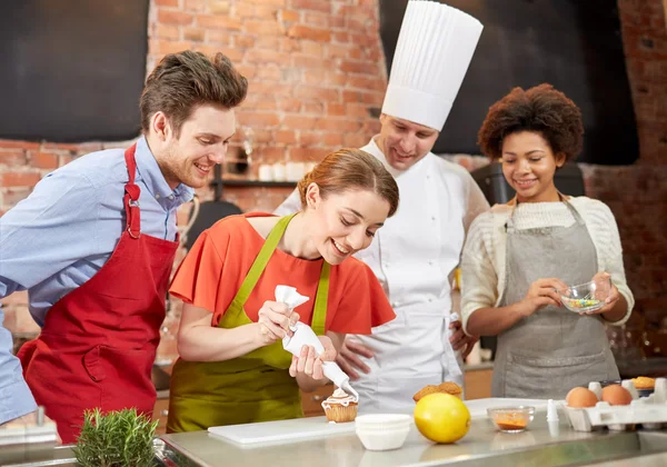 Happy friends and chef cook baking in kitchen — Stock Photo, Image