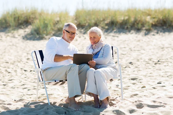 Feliz pareja de ancianos con tableta pc en la playa de verano —  Fotos de Stock