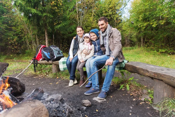 Happy family sitting on bench at camp fire — Stock Photo, Image