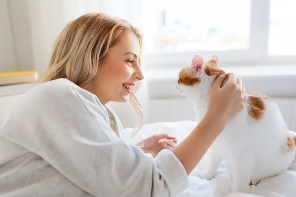 Gelukkig jonge vrouw met kat in bed thuis Stockfoto