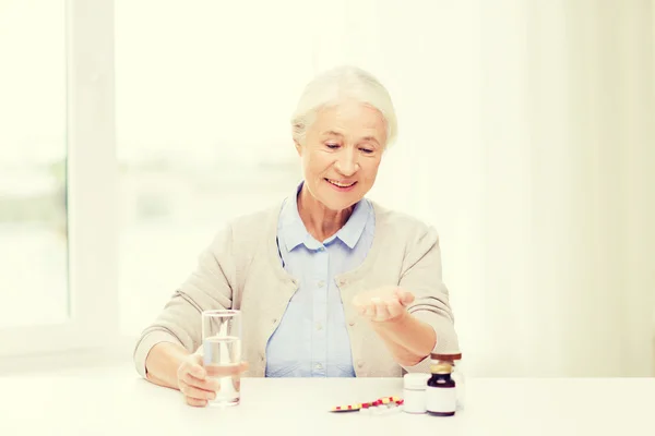 Mulher sênior feliz com água e medicina em casa — Fotografia de Stock