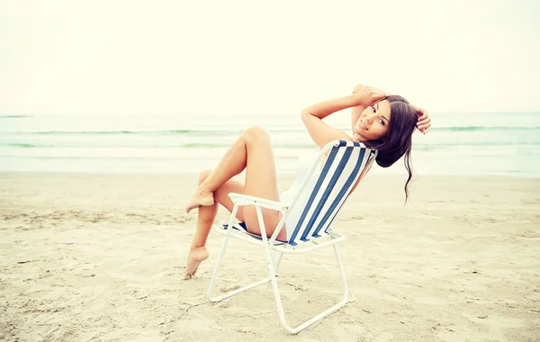 Sonriente joven tomando el sol en el salón en la playa — Foto de Stock