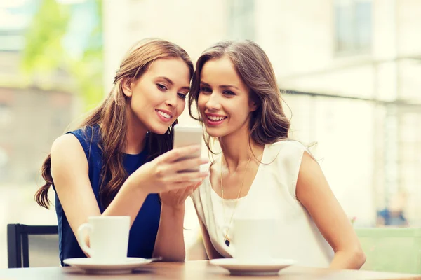 Mujeres jóvenes con teléfono inteligente y café en la cafetería — Foto de Stock