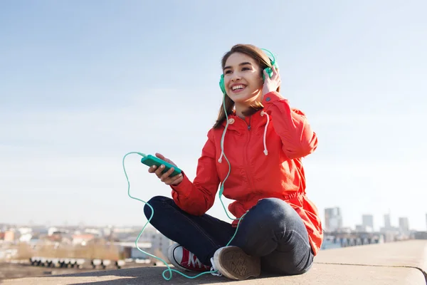 Gelukkig jonge vrouw met smartphone en hoofdtelefoons — Stockfoto