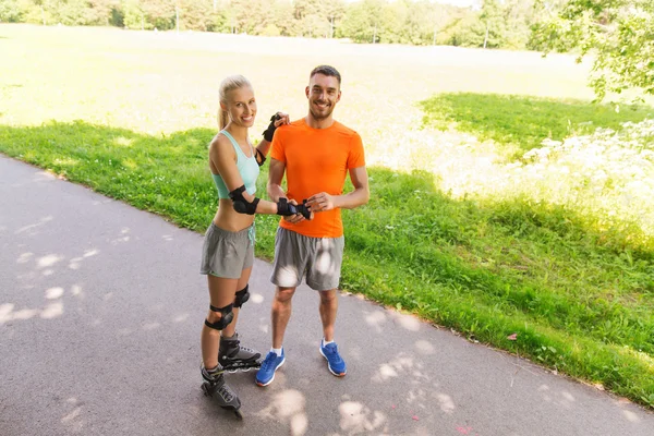 Feliz casal com patins andar ao ar livre — Fotografia de Stock