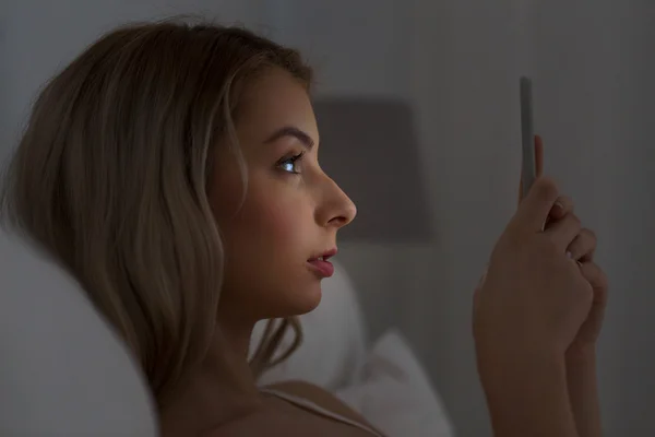 Jeune femme avec smartphone au lit la nuit — Photo