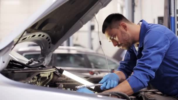 Mechanic man with wrench repairing car at workshop — Stock Video