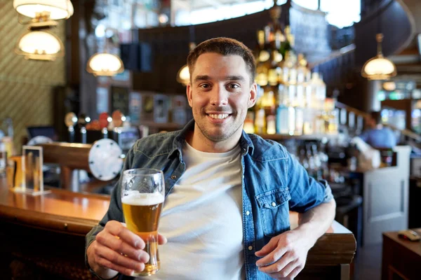 Homem feliz bebendo cerveja rascunho no bar ou pub — Fotografia de Stock