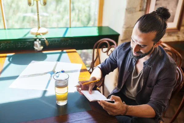 Hombre con cerveza escribiendo a un cuaderno en un bar o pub — Foto de Stock