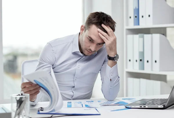 Stressed businessman with papers at office — Stock Photo, Image